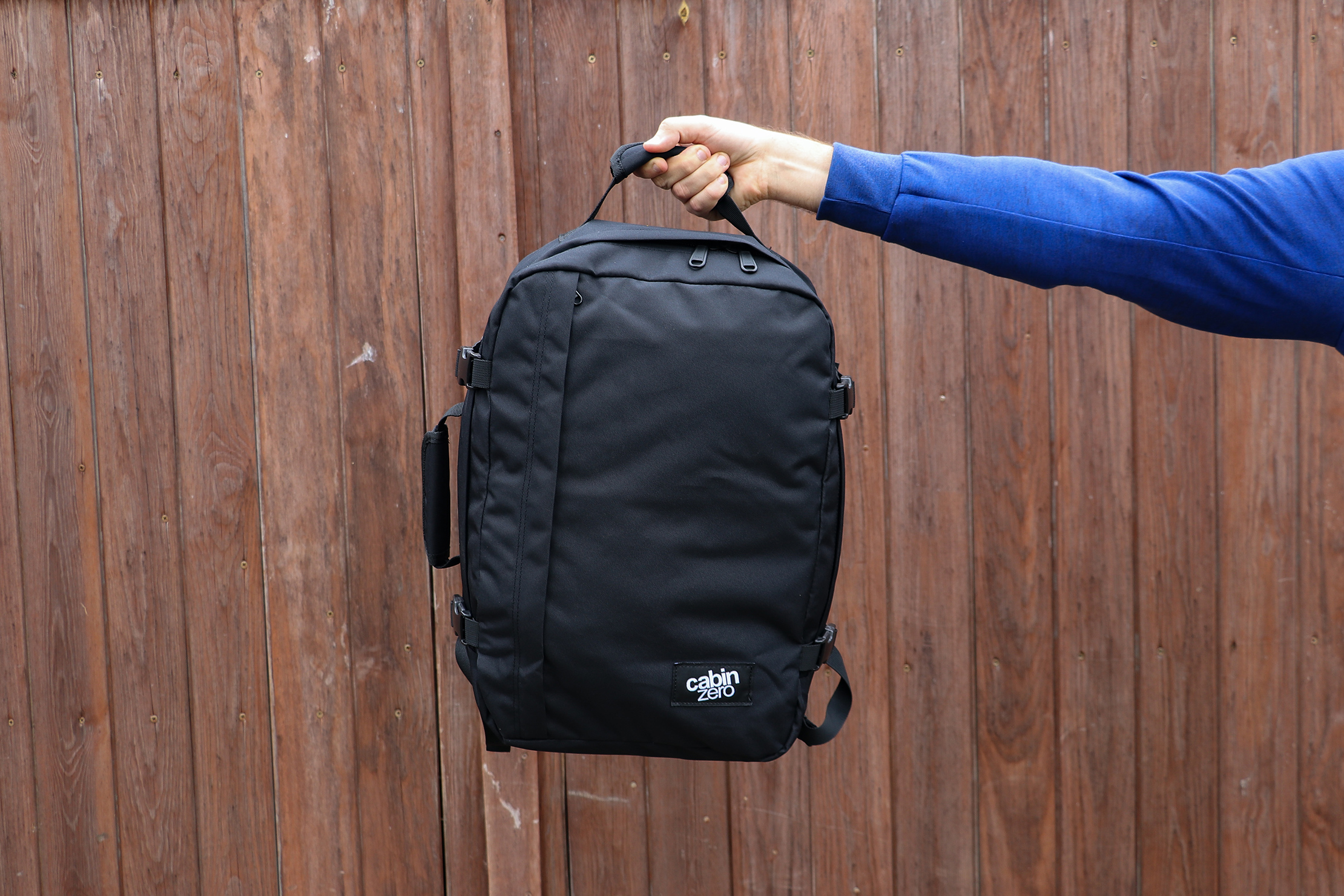 Holding The CabinZero Classic Travel Backpack With The Top Handle