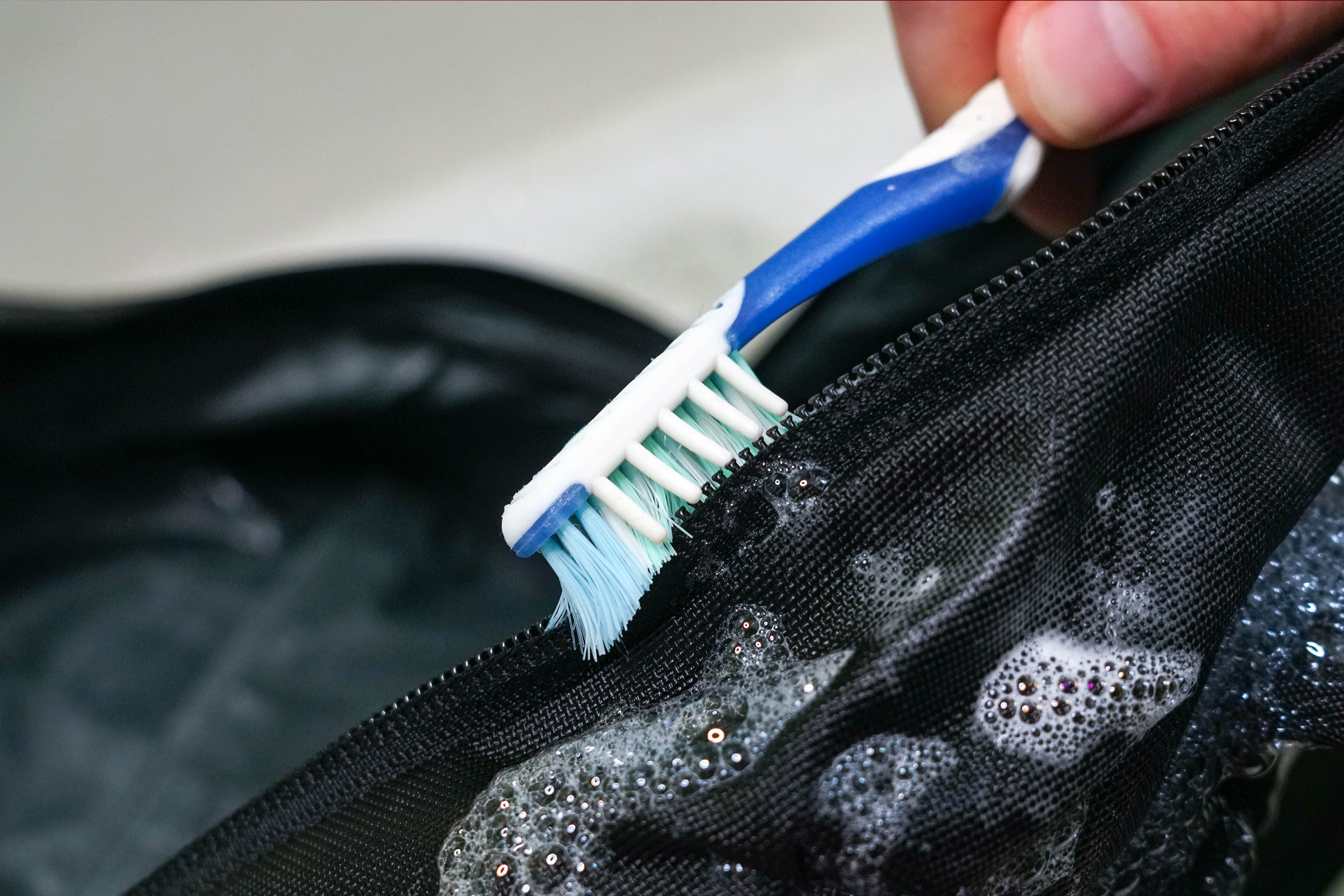 Scrubbing Zippers with Toothbrush